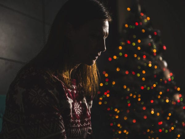 Depressed Person in front of Christmas Tree